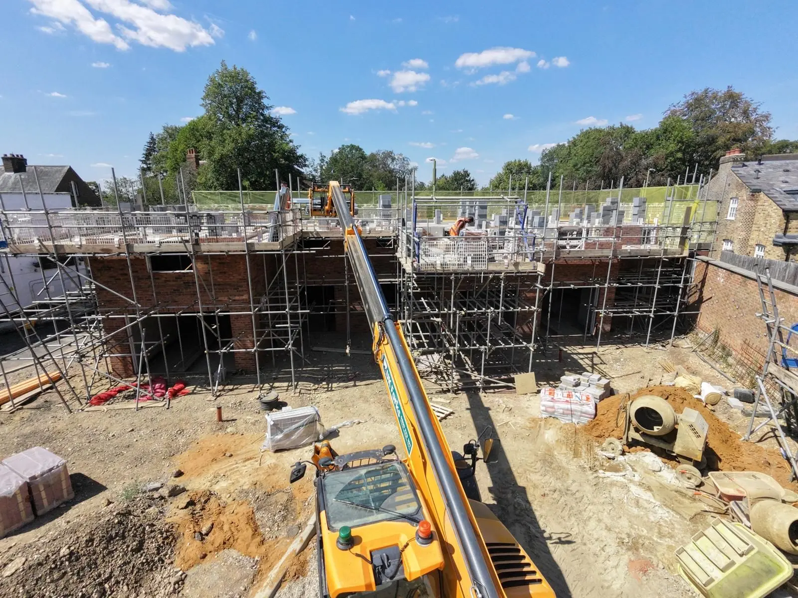 Scaffolding with edge protection erected around a new build development under construction on a sunny day