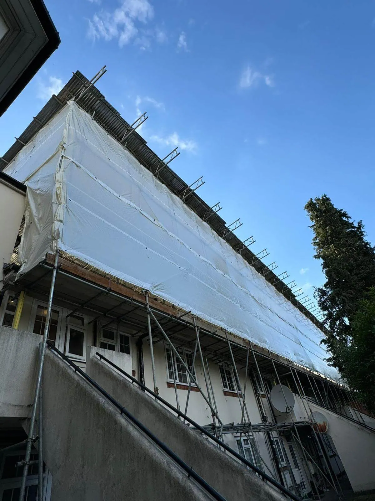 Temporary roof scaffolding with fully sheeted encapsulation keeping a building watertight during roof works