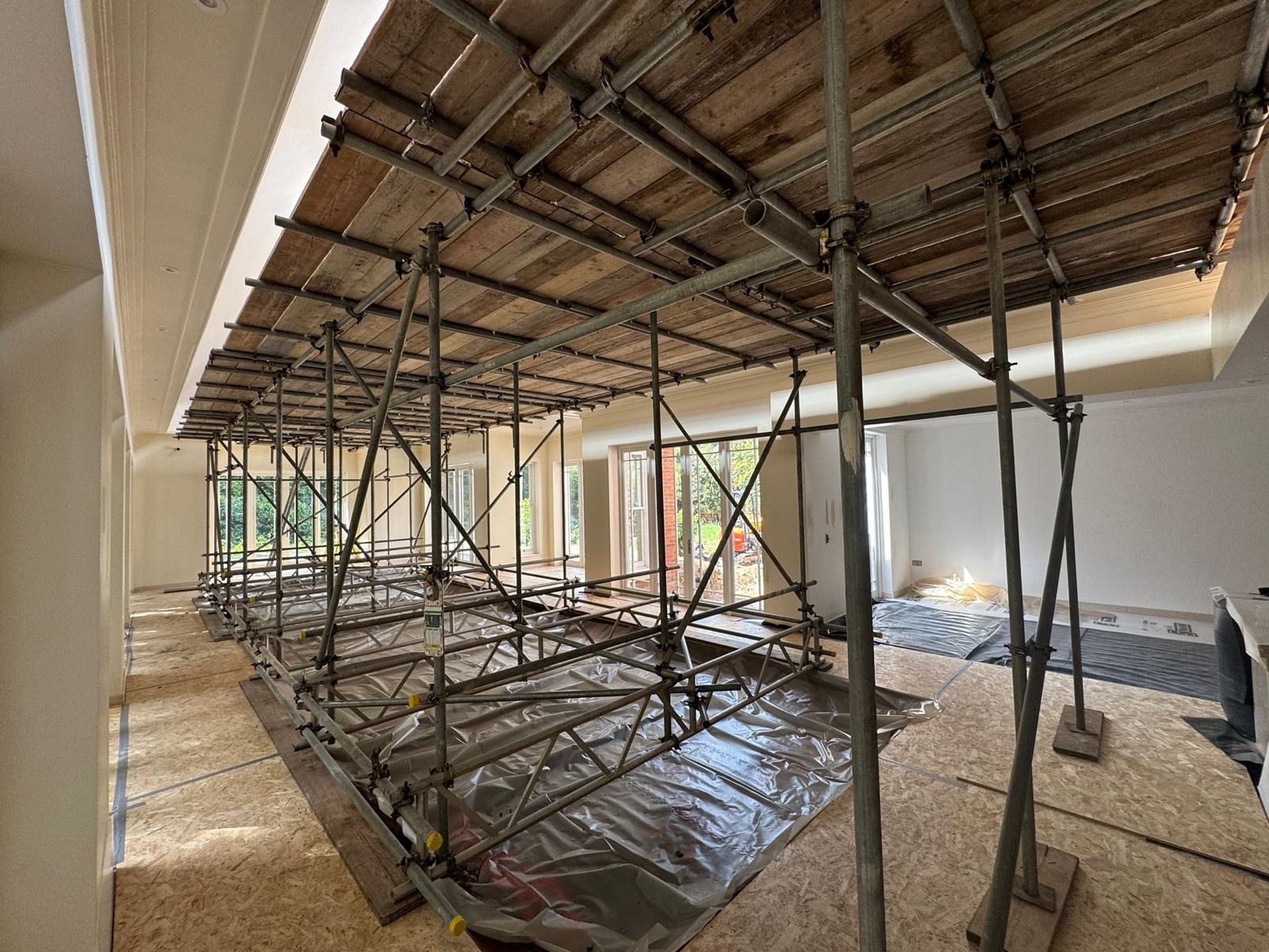 Boarded back propping scaffold carrying exposed ceiling joists across a full room during structural alterations