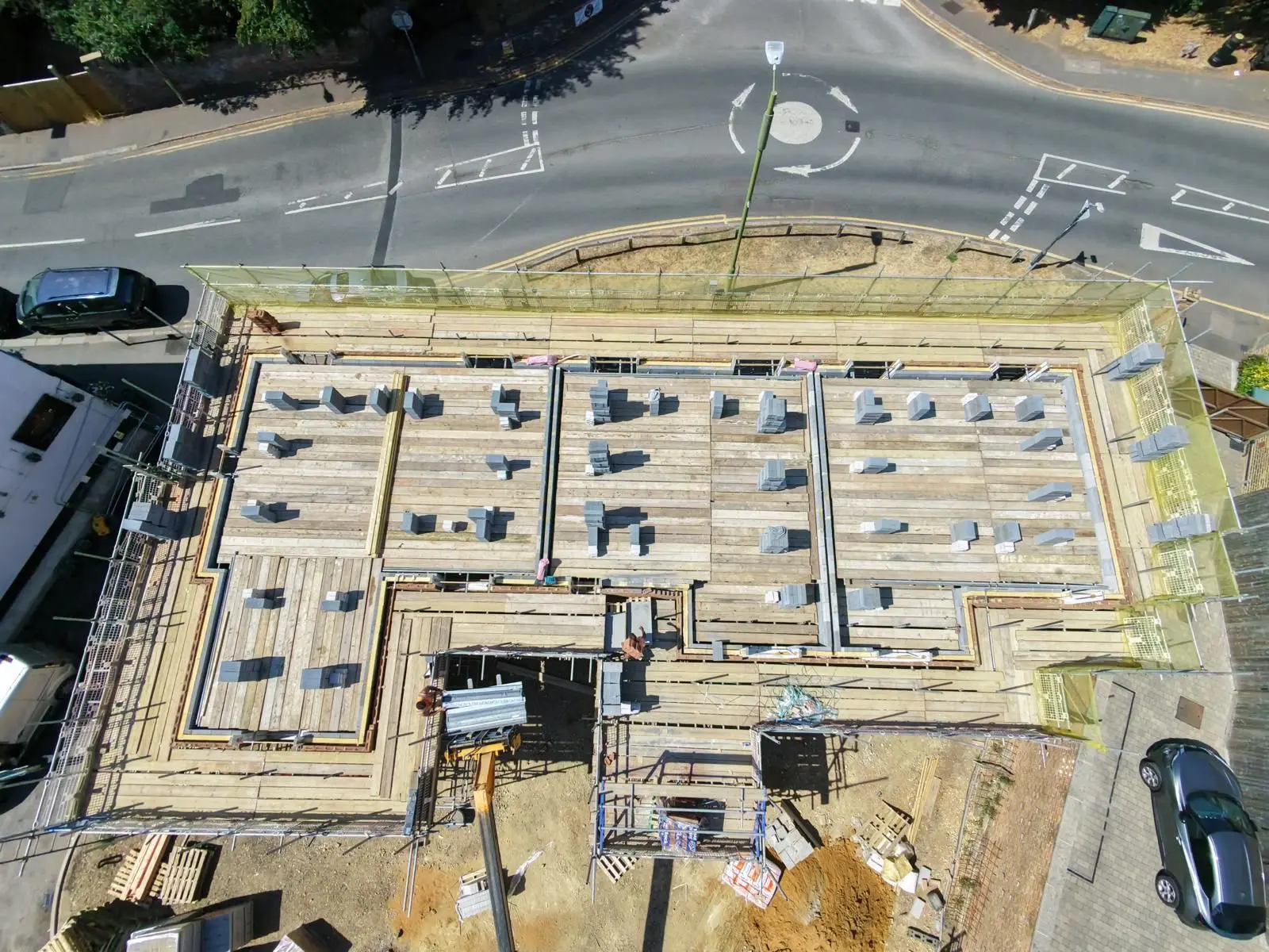 Aerial view of a new build development with fully boarded scaffolding and crash deck at roof level