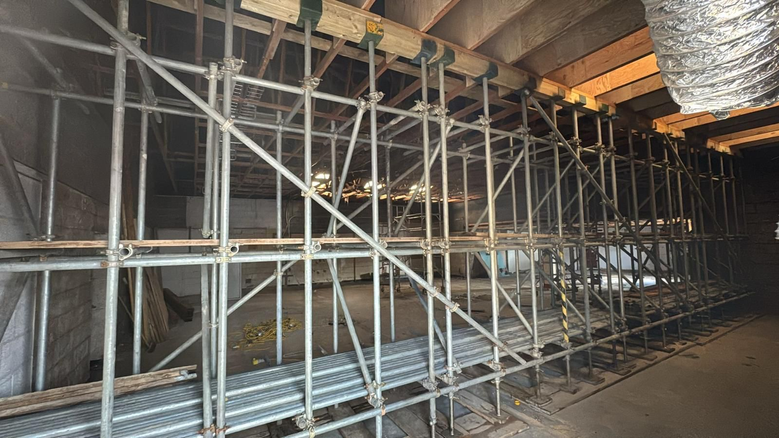 Internal shoring and back propping scaffold supporting timber floor joists across a stripped-out building