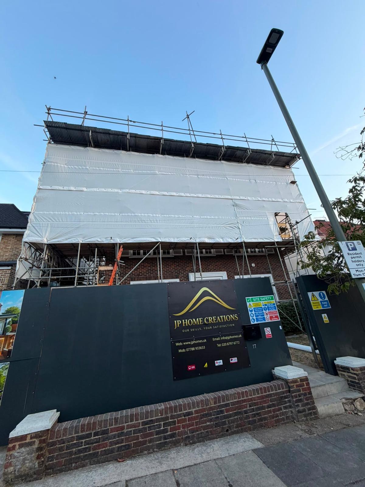 House enclosed in sheeted scaffolding with a loading position for getting materials to roof level