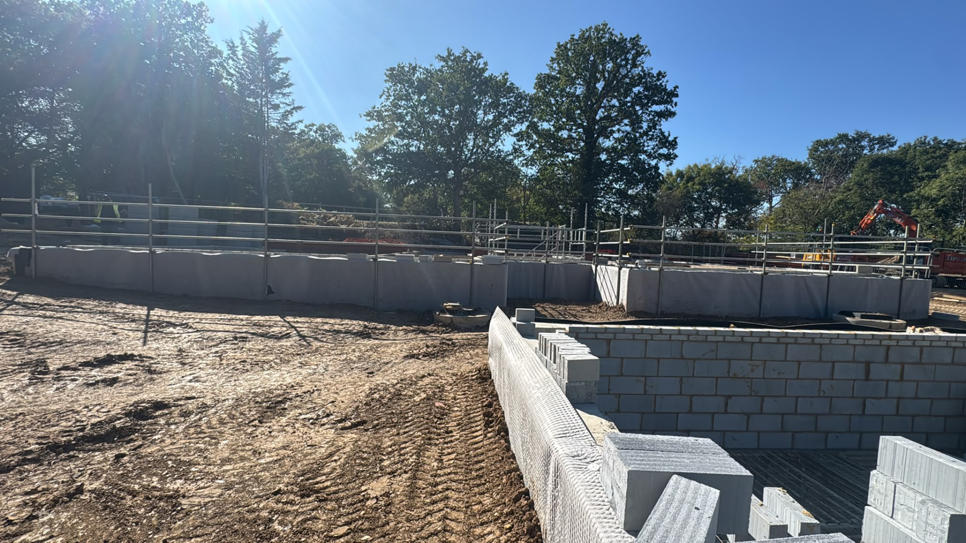 Continuous scaffold edge protection running along a retaining blockwork wall to guard the open drop below