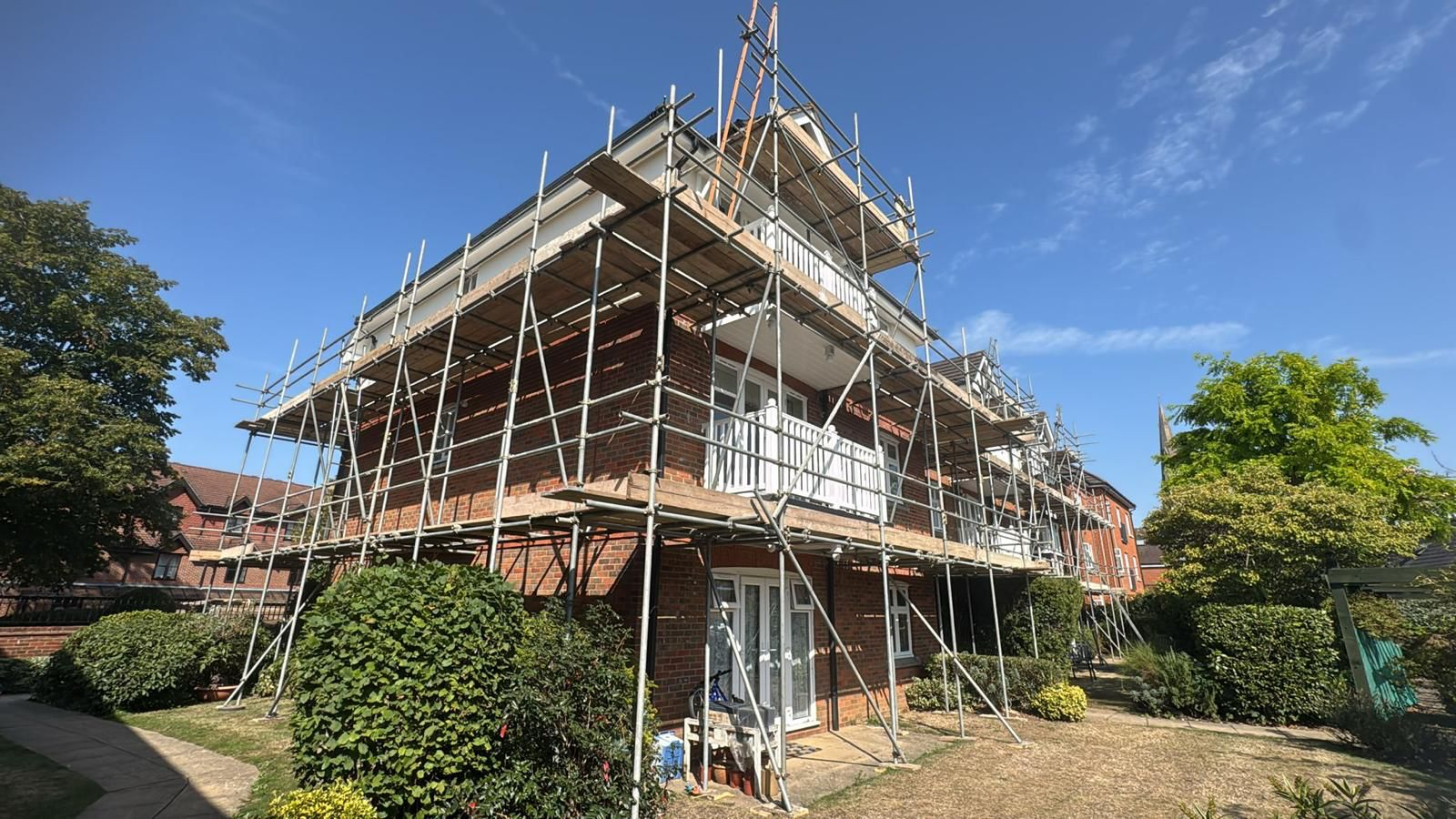 Full perimeter scaffold around a red brick apartment block for roof and facade works